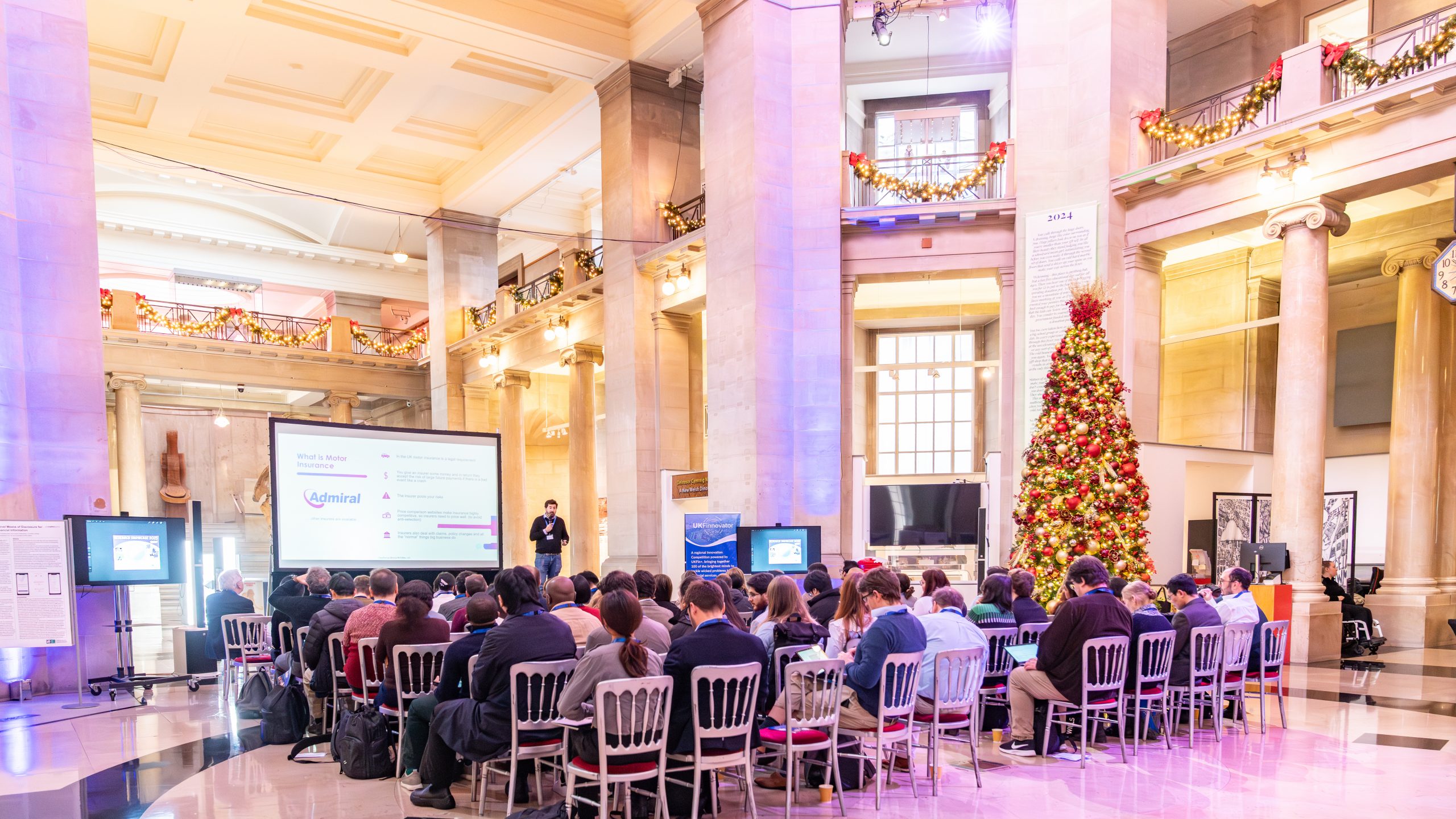 cardiff musuem hall with clement stross presenting to an audience next to a christmas tree